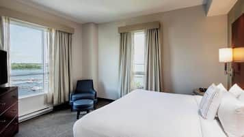 Quarto de hotel com uma cama grande, uma cadeira, uma cômoda e uma televisão.