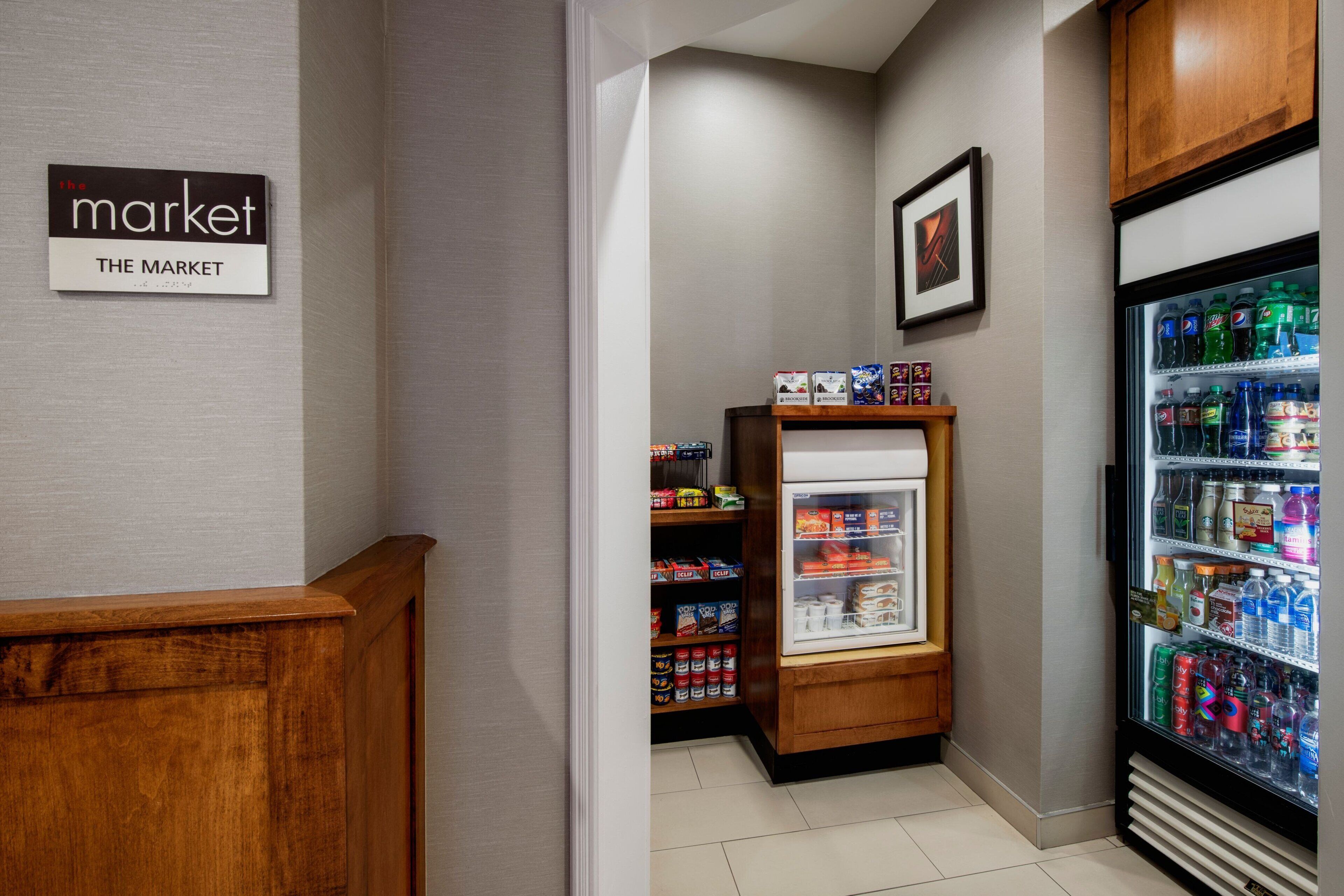 A small market area with a refrigerated display case and shelves stocked with snacks and beverages.