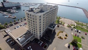 A high-rise hotel with a parking lot and a marina in the background. - Residence Inn by Marriott Kingston Water's Edge (Kingston)
