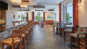 A modern restaurant with a bar area, multiple seating options, and large windows offering views of the outdoors. - Residence Inn by Marriott Kingston Water's Edge (Kingston)