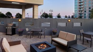 An outdoor patio with a fire pit, seating, and a grill. - Residence Inn by Marriott Kingston Water's Edge (Kingston)