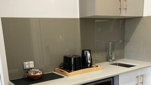 Cocina compacta con horno integrado, microondas y un lavamanos pequeño.