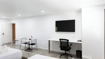 A modern hotel room with a bed, a desk, a chair, and a TV.
