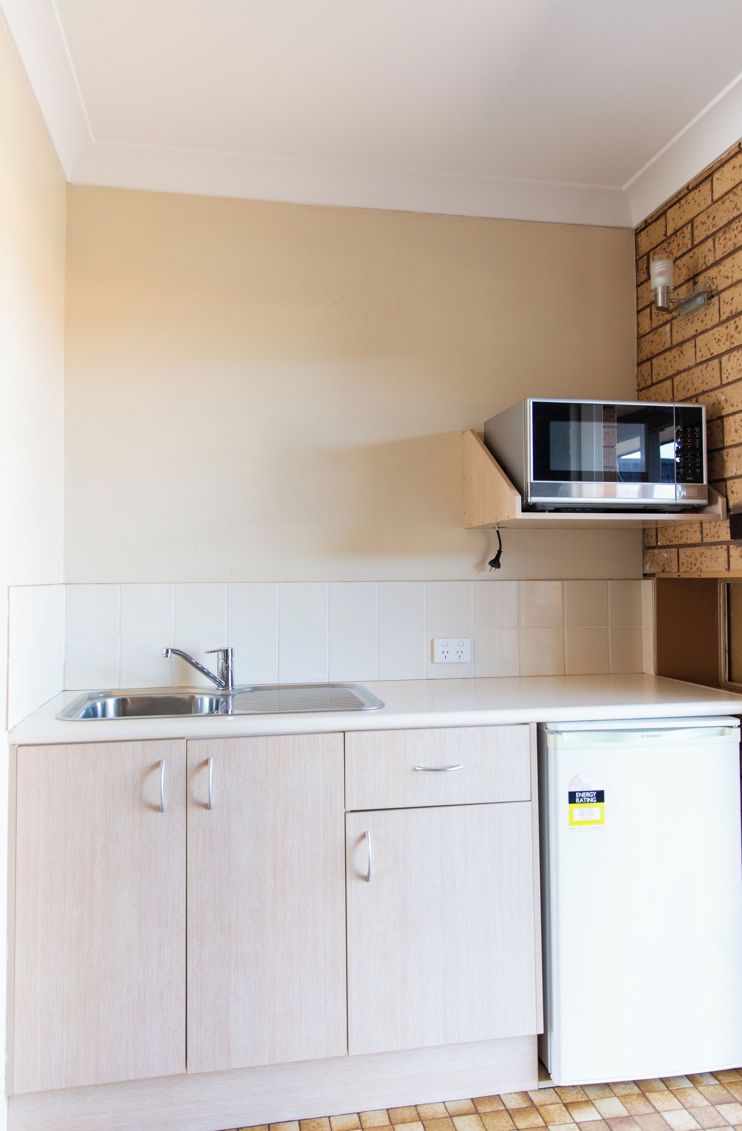A kitchen with a built-in microwave, a sink, and light-colored cabinets.