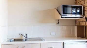 A kitchen with a built-in microwave, a sink, and light-colored cabinets.