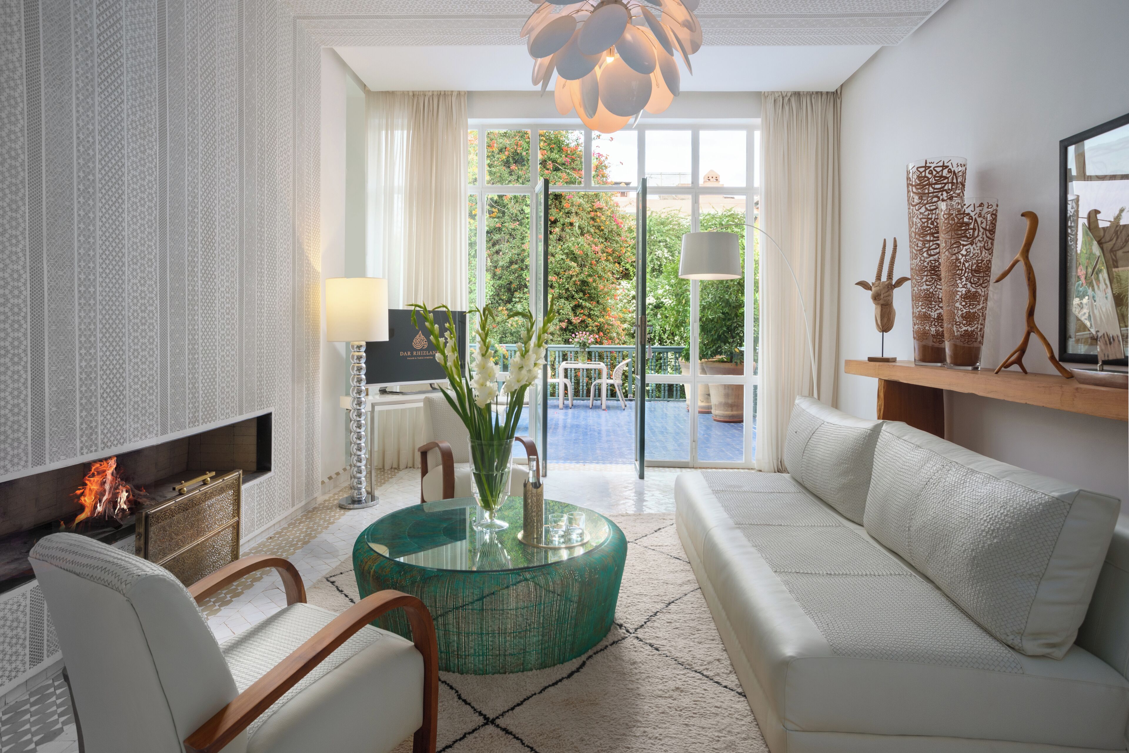 Una sala de estar moderna con chimenea, una mesa de centro de vidrio, un sofá y vistas al exterior a través de amplias ventanas.