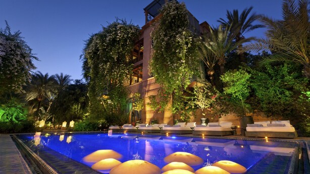 A pool area with lounge chairs and a building with a unique architectural design. - Dar Rhizlane (Marrakech)