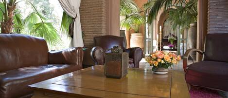 Un lobby acogedor con sofás de cuero, una mesa de centro de madera y plantas en macetas.