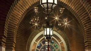 An arched hallway with a chandelier, a fountain, and a view into a garden. - Dar Rhizlane (Marrakech)