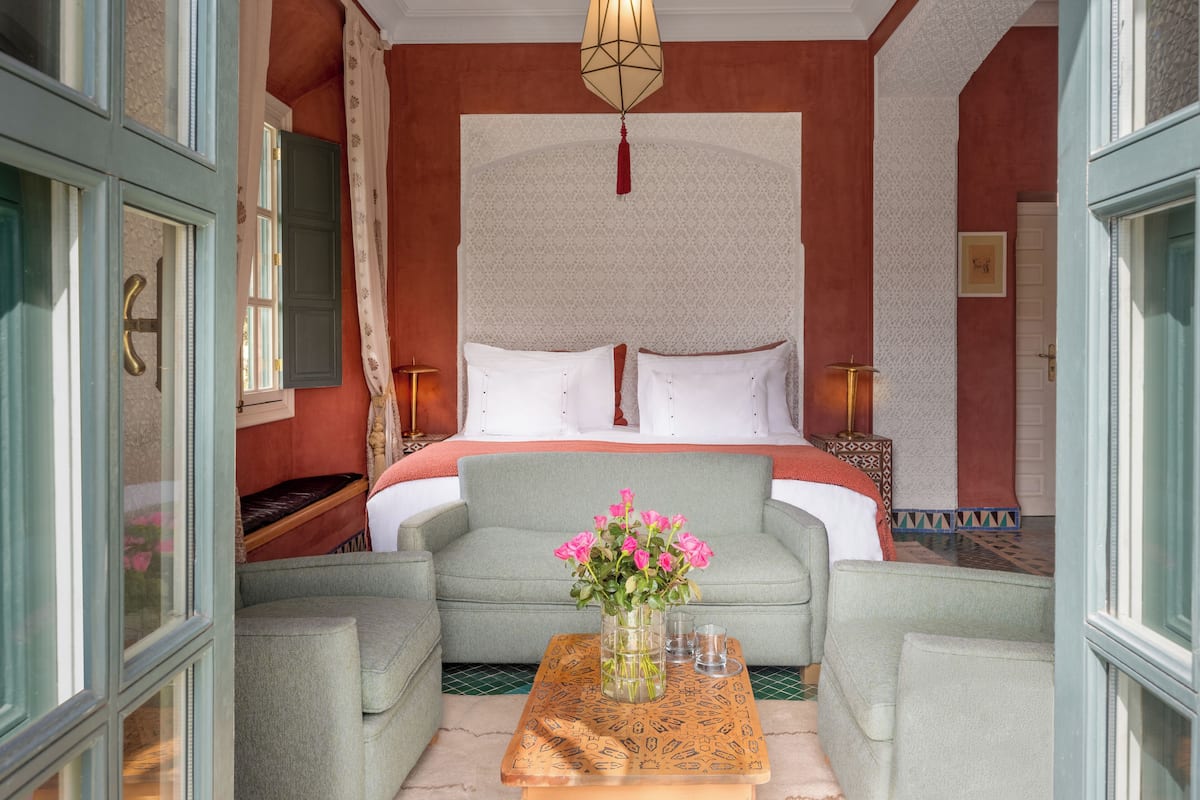A hotel room with a bed, two armchairs, a coffee table, and a decorative wall.