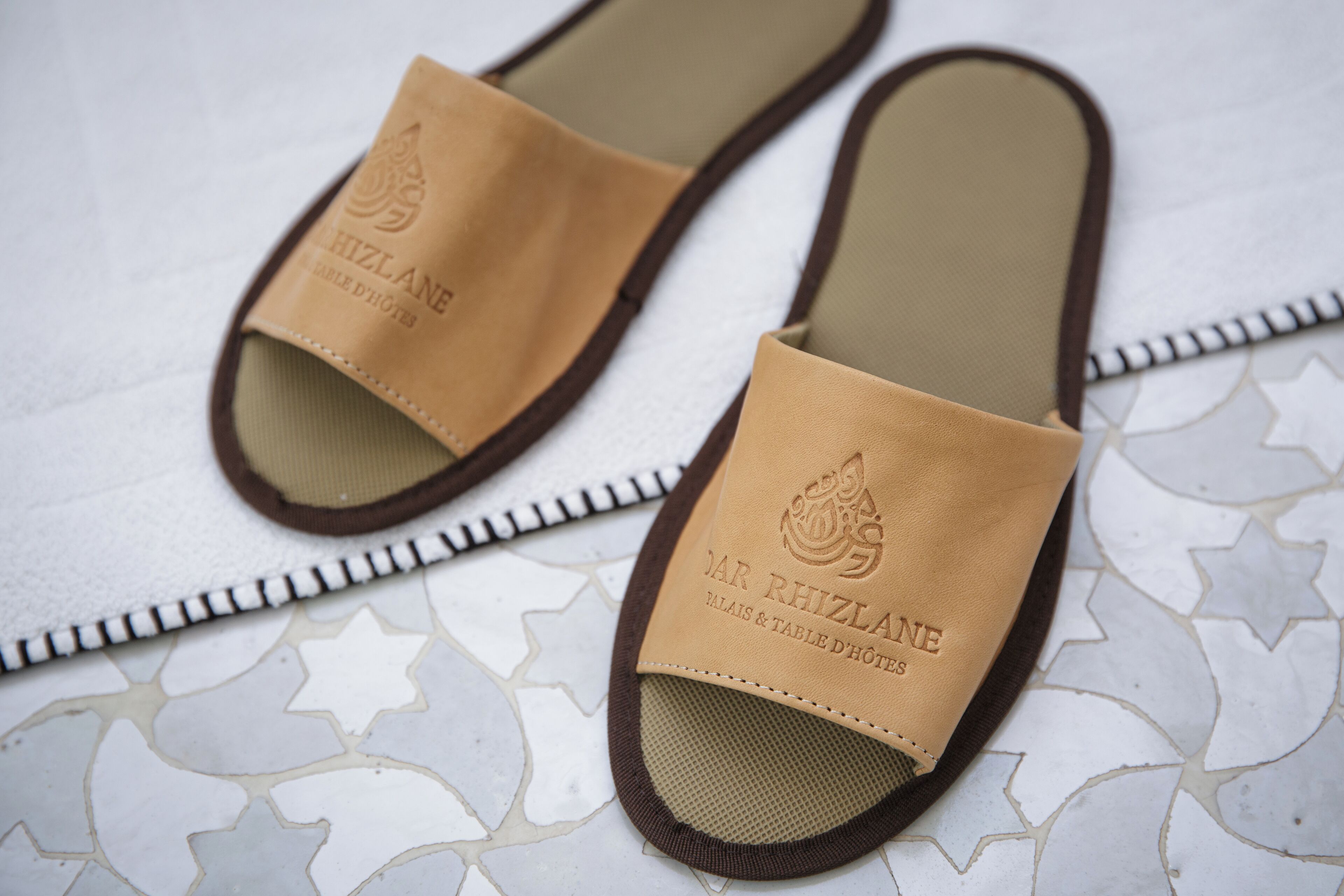 A pair of slippers with embossed text on the strap.