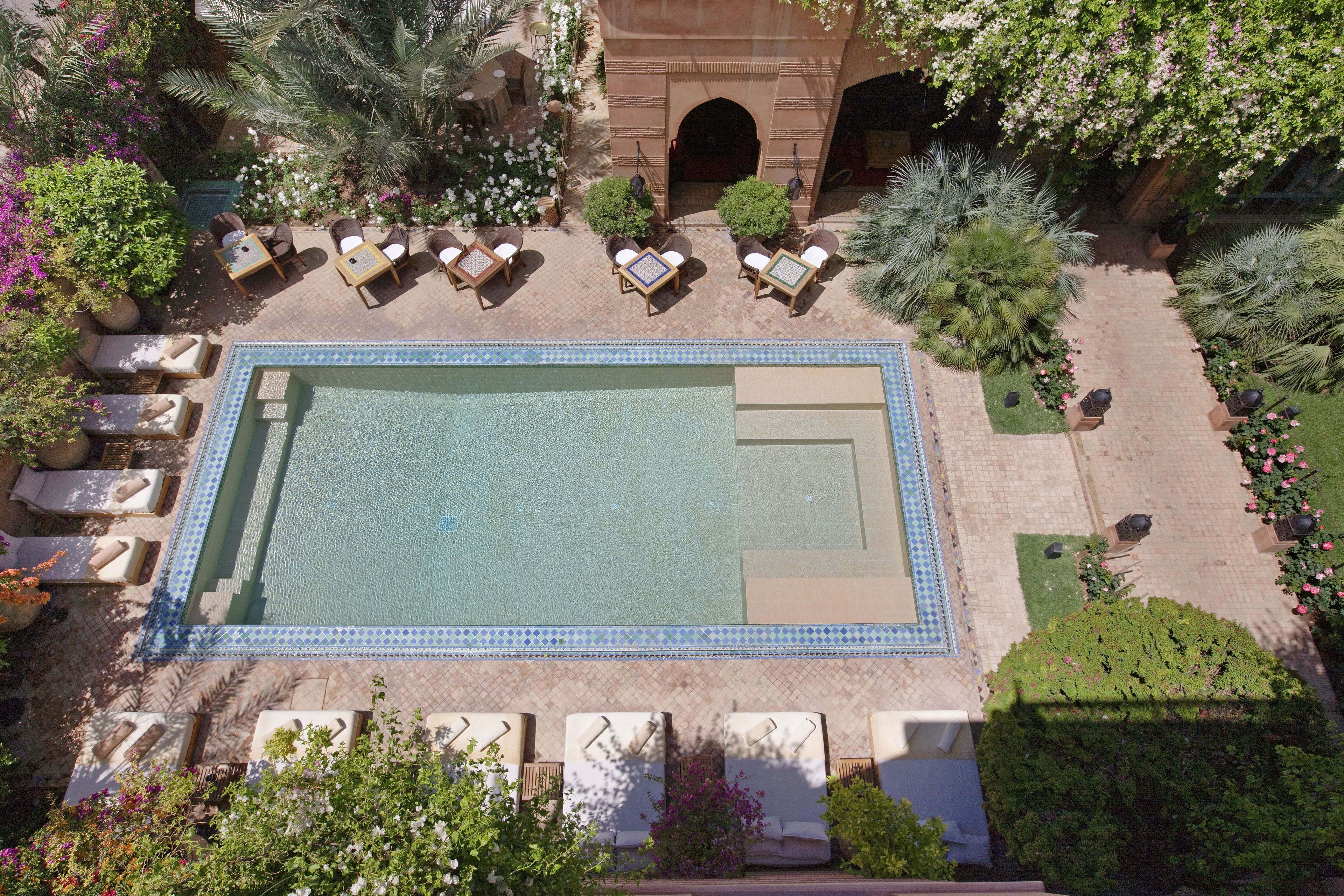 Vista aérea de un área de piscina con sillas de descanso y una pileta.