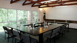 Uma sala de conferências com uma mesa comprida, cadeiras e grandes janelas que dão para as árvores.