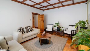 A spacious living room with a high ceiling, wooden beams, a sofa, two armchairs, a coffee table, and potted plants. - Lake Lodge B&B Rotorua - Adults Only (Rotorua)