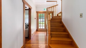 A wooden staircase leading to a second floor, a door with frosted glass panels, and a hallway with a patterned rug. - Lake Lodge B&B Rotorua - Adults Only (Rotorua)