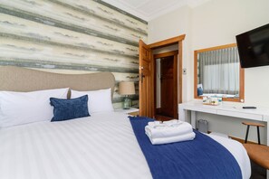 A hotel room with a bed, a desk, a chair, a TV, and a bathroom door. - Lake Lodge B&B Rotorua - Adults Only (Rotorua)