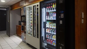 Un área de venta automática con diversas máquinas expendedoras de bebidas y aperitivos, incluyendo un refrigerador Coca-Cola y un refrigerador Vendo.