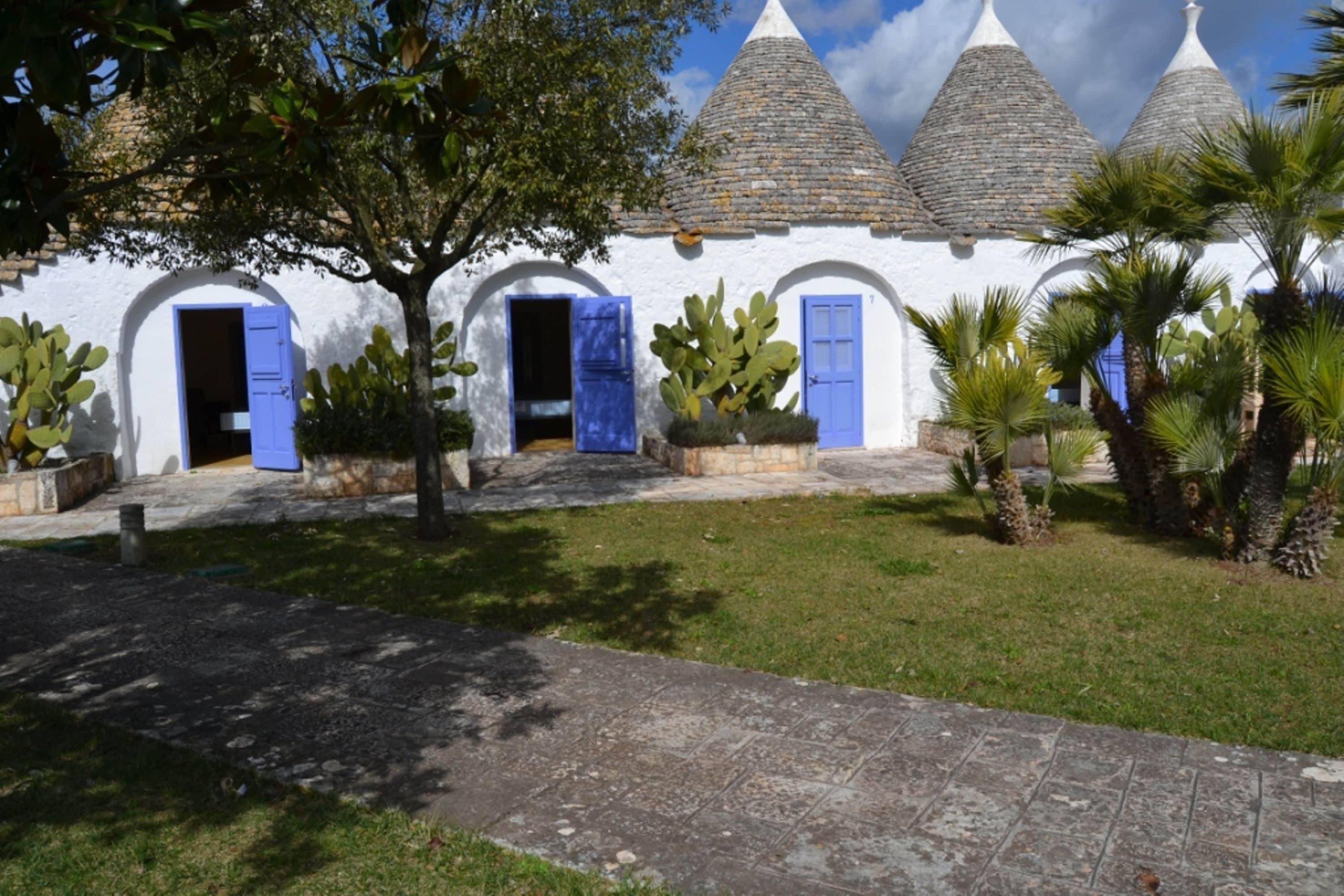 A white building with blue doors and a stone roof.