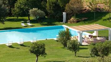 Relax by the pool surrounded by lush greenery and comfortable lounge chairs.