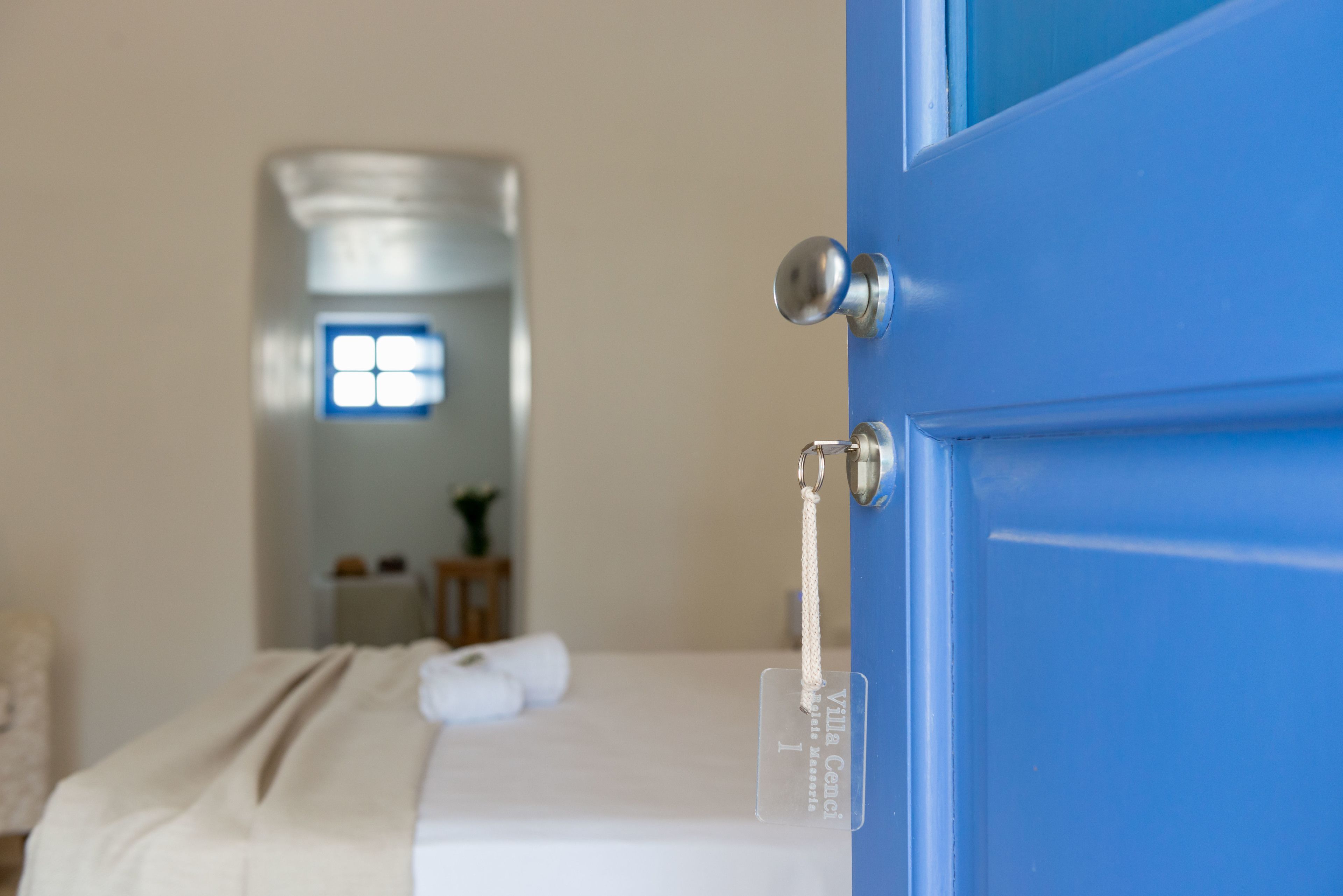 Una habitación con una cama, una puerta azul y una ventana con vistas.