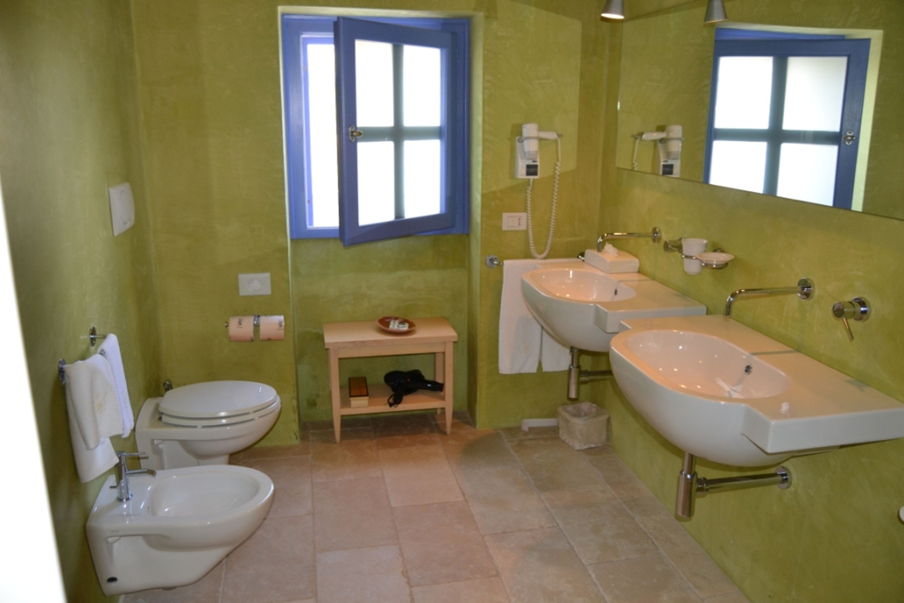 Un baño con inodoro, bidé y dos lavabos.