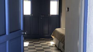 Une pièce avec un sol à carreaux, un lit et une porte avec une fenêtre.
