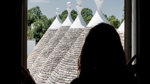 Vista a través de una ventana de un edificio con techo de piedra y detalles arquitectónicos blancos y puntiagudos.