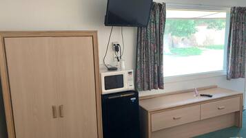 A room with a bed, a desk with a computer, a television, and a wardrobe.