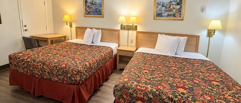 Habitación de hotel con dos camas, un escritorio y dos lámparas de pared.