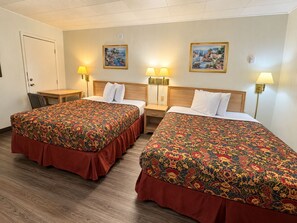 A hotel room with two beds, a desk, and two wall-mounted lamps. - Budget Lodge Inn Abilene KS (Abilene)