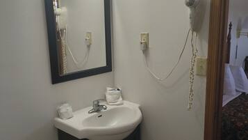 A bathroom with a sink, mirror, hairdryer, and lights.