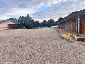 A parking lot with a building on the right and trees in the background. - Budget Lodge Inn Abilene KS (Abilene)