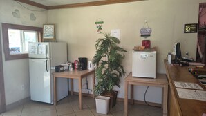 Cocina compacta con refrigerador, cafetera y planta en maceta.