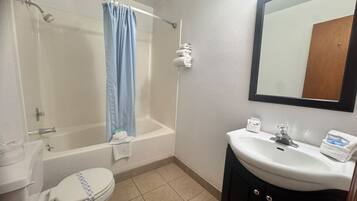 A bathroom with a shower, toilet, sink, and a mirror.