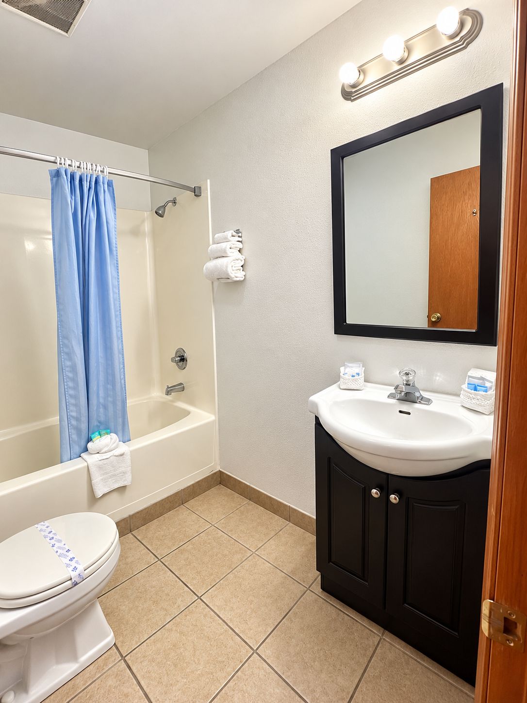 A bathroom with a bathtub, toilet, sink, and mirror.