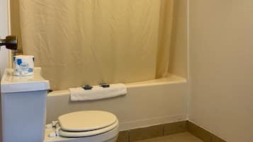 A bathroom with a toilet, a bathtub, and a shower curtain.