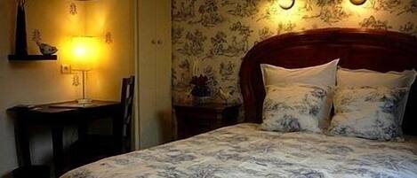 A bedroom with a bed, a nightstand, a lamp, and a chair.