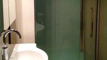 Bany amb un rentamans blanc, un mirall i una cabina de dutxa de vidre.
