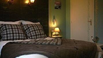 Un dormitorio con cama, dos almohadas, una mesita de noche y una lámpara, y una puerta.
