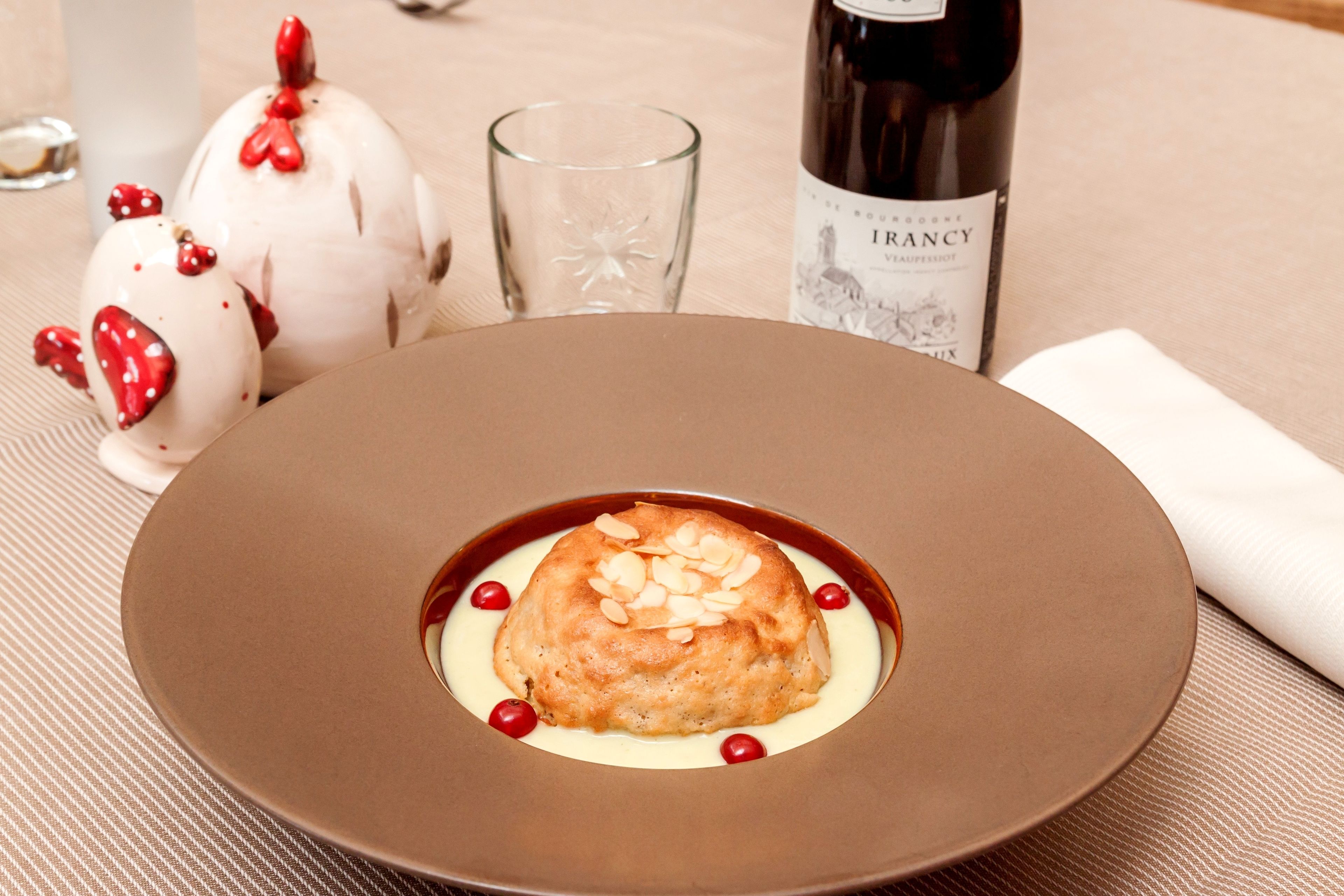 A dessert on a plate with a bottle of wine and a glass in the background.