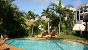 Una piscina al aire libre, sombrillas, sillones reclinables de piscina