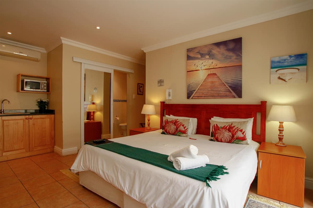 Ein Hotelzimmer mit einem großen Bett, einem Holzschrank, einer Mikrowelle und einem Gemälde eines Piers.