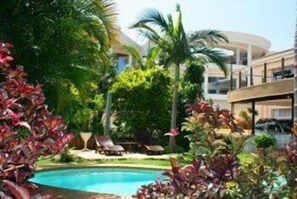 Una piscina al aire libre, sombrillas, tumbonas