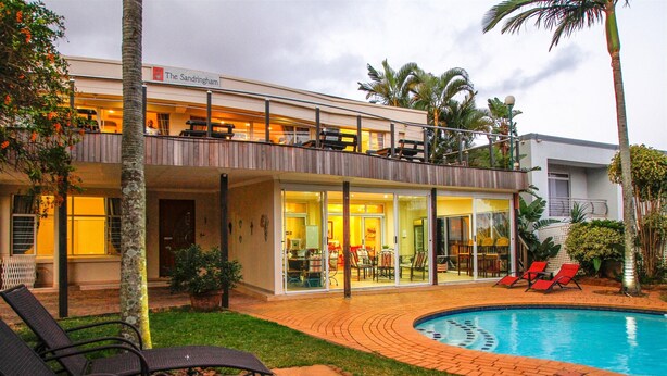 A modern hotel with a pool, outdoor seating, and a covered patio area. - THE SANDRINGHAM B&B AND SELF-CATERING (Umhlanga)