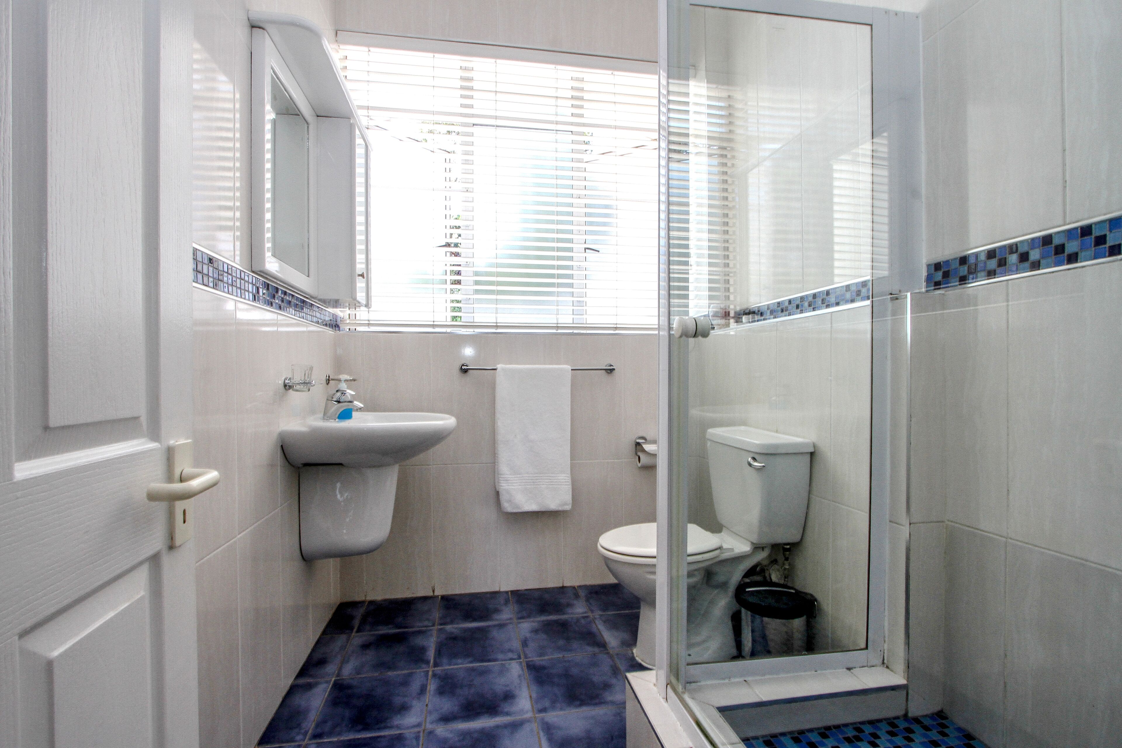 A bathroom with a white sink, toilet, and a glass shower enclosure.