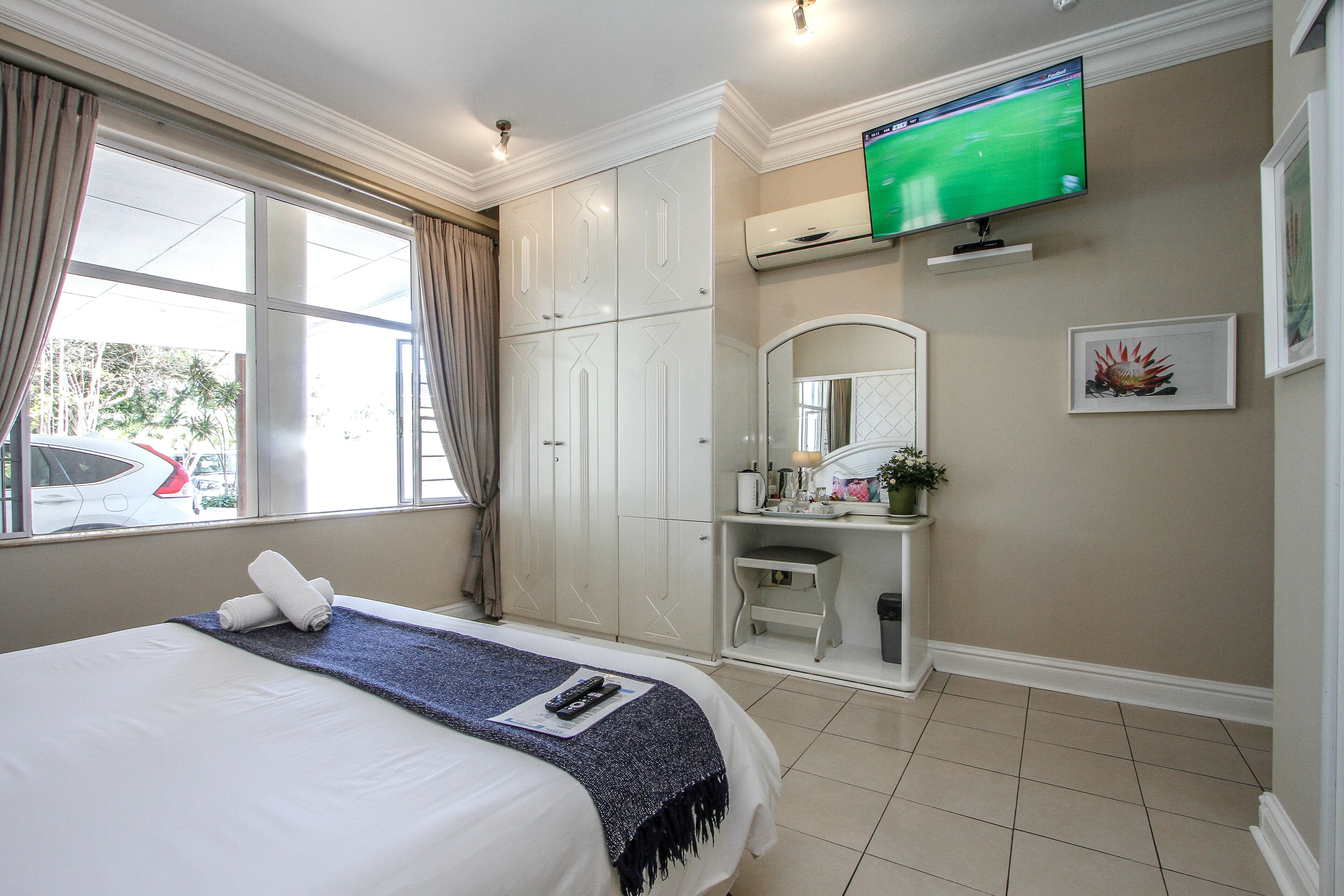 Een hotelkamer met een bed, een bureau, een televisie en een raam met gordijnen.