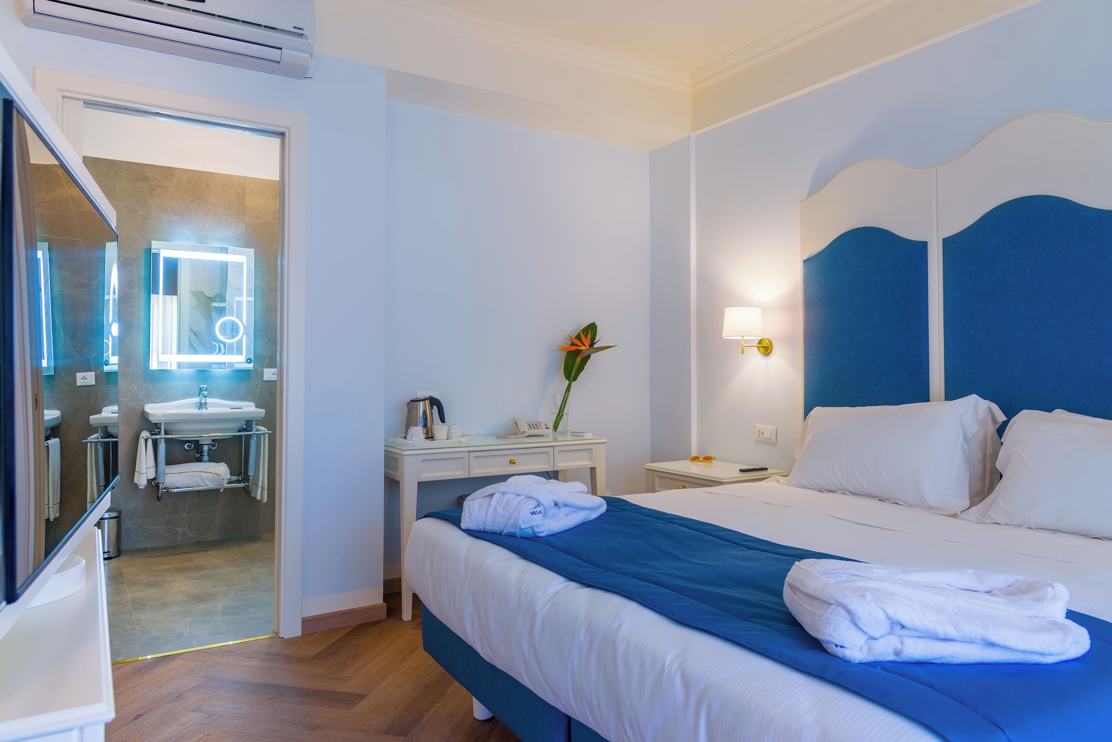 A hotel room with a bed, bedside table, and a bathroom visible through an open door.