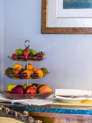 Un puesto de frutas de tres niveles, con diferentes frutas en cada uno.