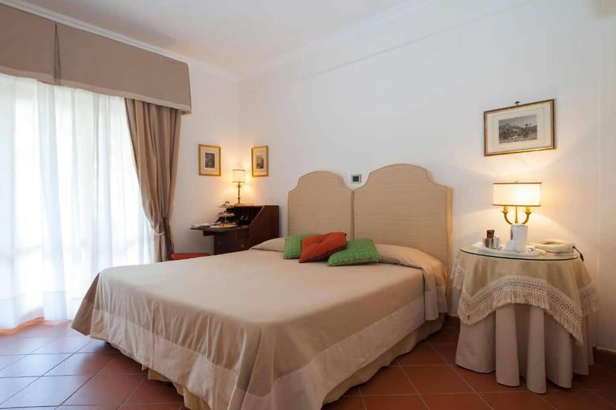Una habitación de hotel con cama, dos mesitas de noche, un escritorio y una silla.