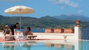 Ein Poolbereich mit Bergblick, ein Kellner serviert Getränke, und eine Zierurne.